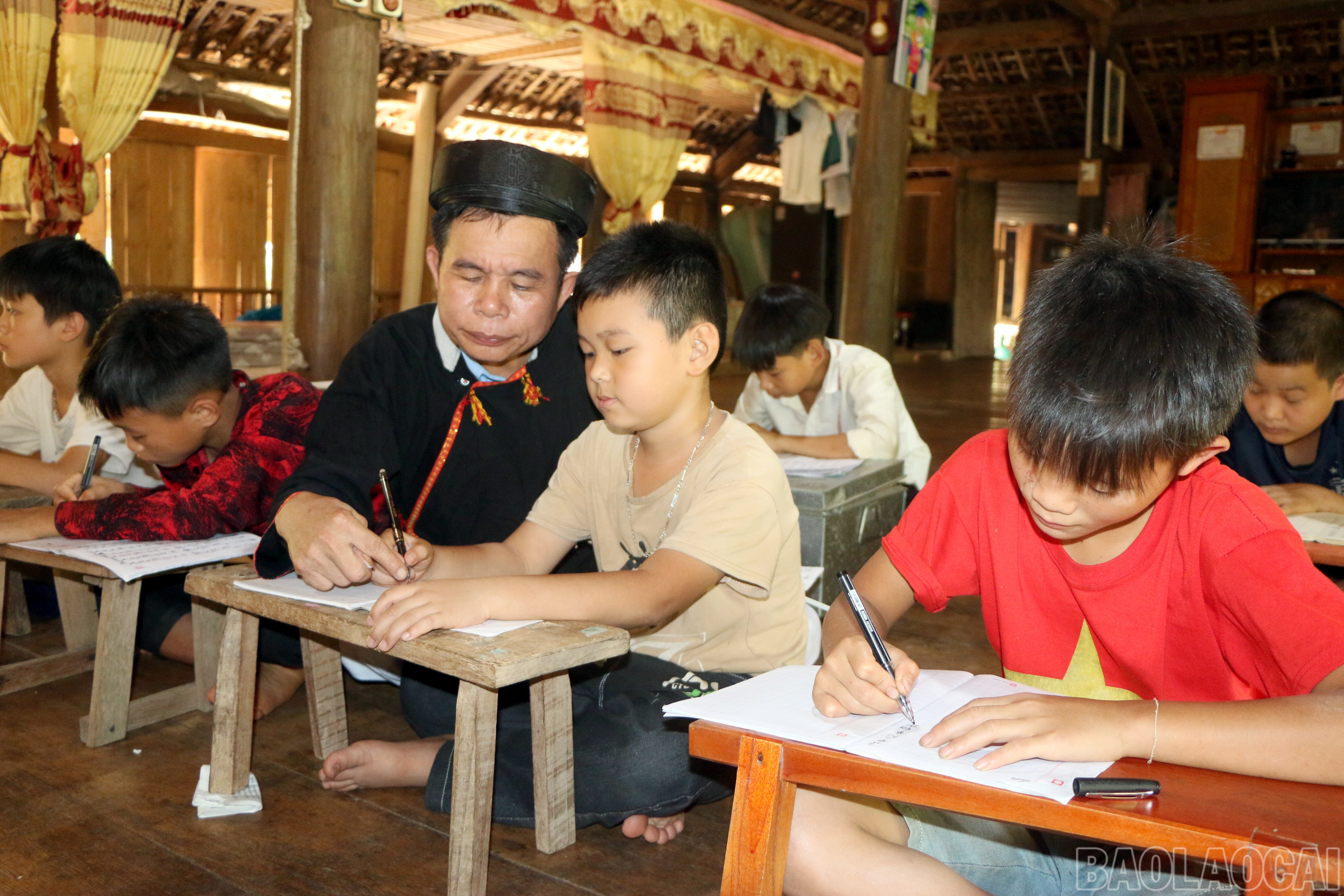 Trong không gian nhà sàn truyền thống, nghệ nhân ưu tú Hoàng Hữu Định (xã Yên Thành) kiên trì hướng dẫn các em nhỏ học viết chữ Dao cổ, một cách trao truyền di sản ngôn ngữ, thắp lên niềm tự hào dân tộc cho thế hệ mai sau. baolaocai-br_img-8688.jpg