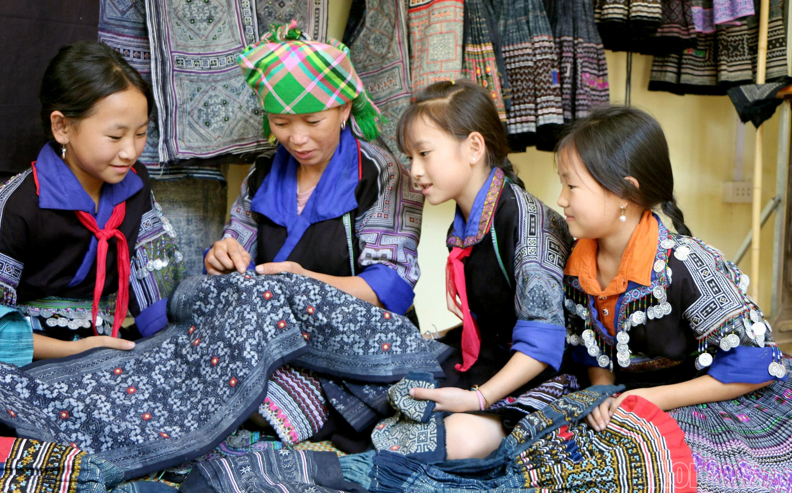 Phụ nữ Mông tỉ mỉ truyền dạy kỹ thuật thêu hoa văn trên nền vải chàm – một trong những biểu tượng đặc trưng của trang phục truyền thống. baolaocai-br_dt-mong.jpg