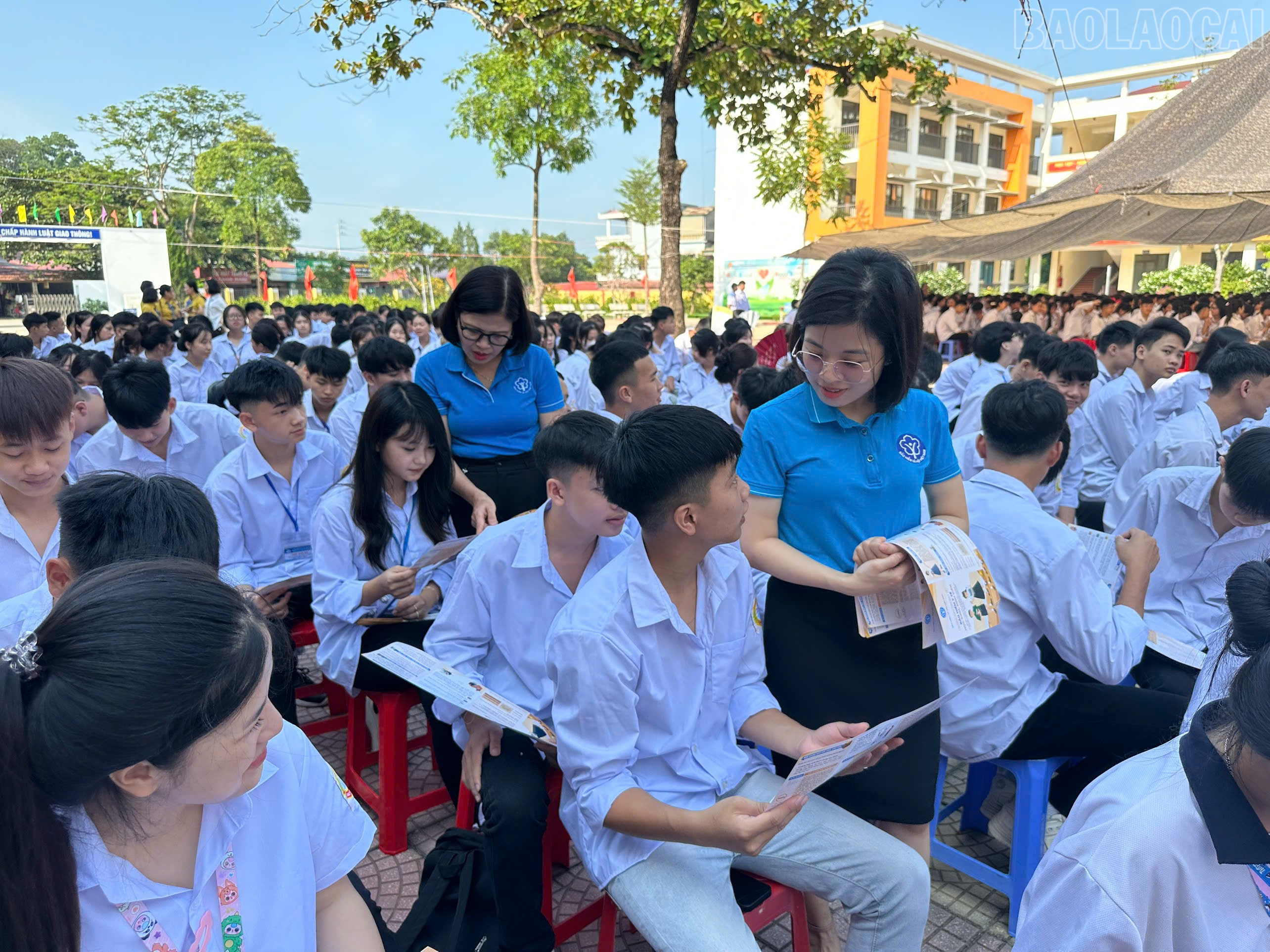Viên chức BHXH tỉnh Lào Cai phát tờ rơi tuyên truyền chính sách BHYT đến các em học sinh. baolaocai-tr_z6988526105039-c3b6ed320b085af4ce88fe43e732c94f.jpg
