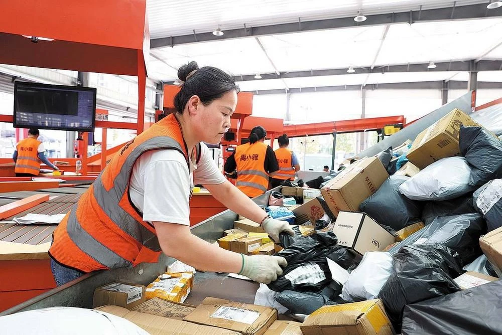 Các nhân viên tại trung tâm phân phối ở Yucheng xử lý bưu kiện với sự trợ giúp của máy phân loại.