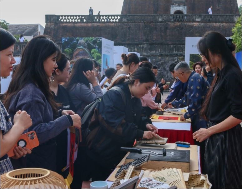 Du khách trải nghiệm in tranh Đông Hồ tại Khu di tích Hoàng thành Thăng Long.