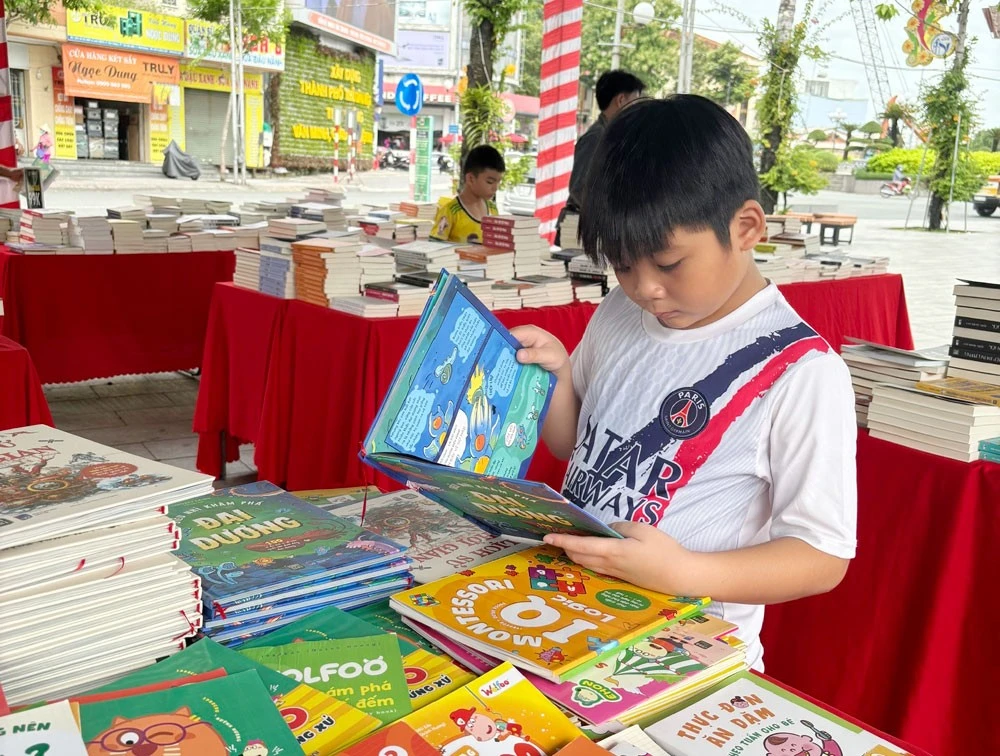 Một bạn thiếu nhi say sưa với quyển truyện tranh tại Hội sách hè được tổ chức ở Công viên ngã 6, phường Phú Cường, TP.Thủ Dầu Một.