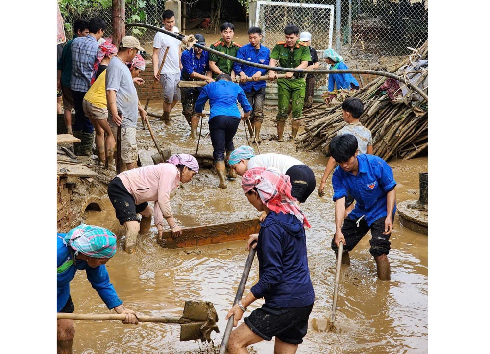 Chung tay giúp người dân xử lý bùn đất sau ngập.