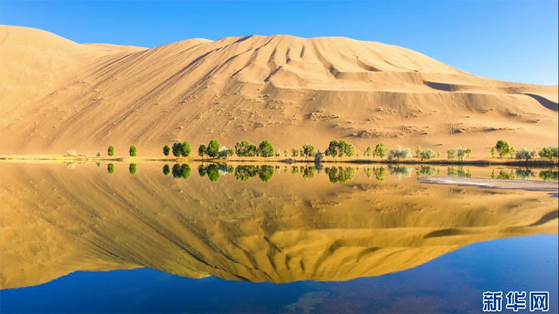 Núi cát soi bóng xuống hồ nước trên sa mạc Badain Jaran.