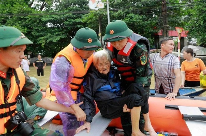 Cụ Nguyễn Thị Kỳ, 98 tuổi, ở xã Sơn Đông, huyện Lập Thạch, tỉnh Vĩnh Phúc được các chiến sĩ bộ đội giúp đỡ đưa lên thuyền cứu hộ đưa đến nơi an toàn.