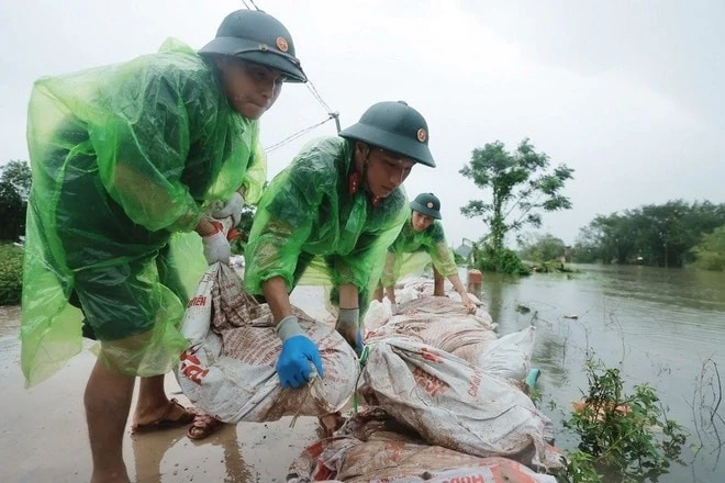 Cán bộ, chiến sĩ Trung đoàn 102 hỗ trợ người dân đắp bao tải đất gia cố đê sông Tích.