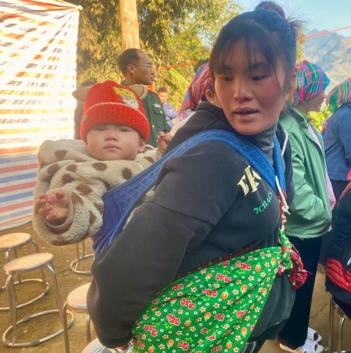 Bà Giàng Thị Hương vui vẻ địu cháu đến nhận quà Tết
