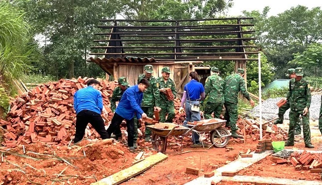 Bộ đội biên phòng và Đoàn thanh niên xã Bản Qua tham gia vận chuyển vật liệu, xây dựng nhà.