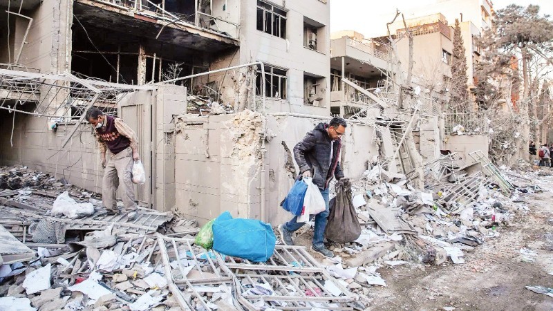 Người dân thu dọn đống đổ nát sau một vụ không kích tại Iran.