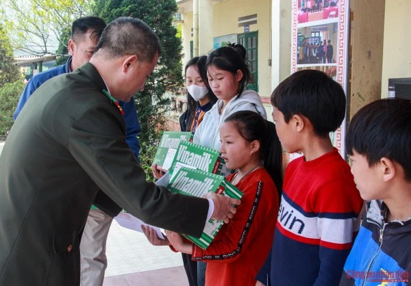Đại tá Trần Duy Hiển, Phó Tổng Biên tập Báo CAND trao quà cho các em học sinh.