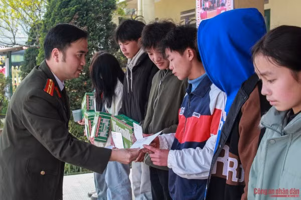 Thiếu tá Trần Quang Huy, Chủ tịch Công đoàn Báo CAND trao quà cho các em học sinh.