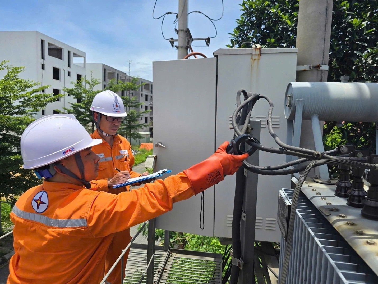 Công nhân EVNNPC kiểm tra thiết bị giữa trưa nắng, đảm bảo vận hành an toàn lưới điện. 1.jpg