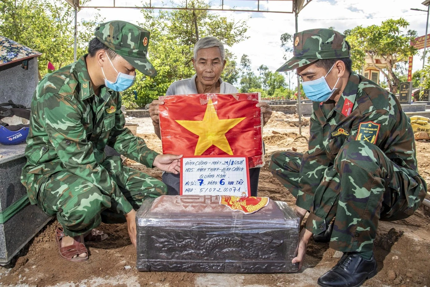 Trên chiếc quan tài được chôn cất trở lại có dán hình Quốc huy, chụp ảnh lưu lại định danh. (Ảnh: Lê Văn Chương)