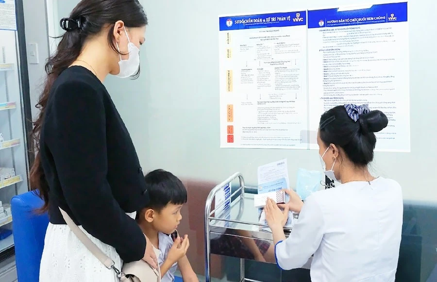Phụ huynh đưa trẻ đi tiêm vắc xin phòng bệnh não mô cầu.