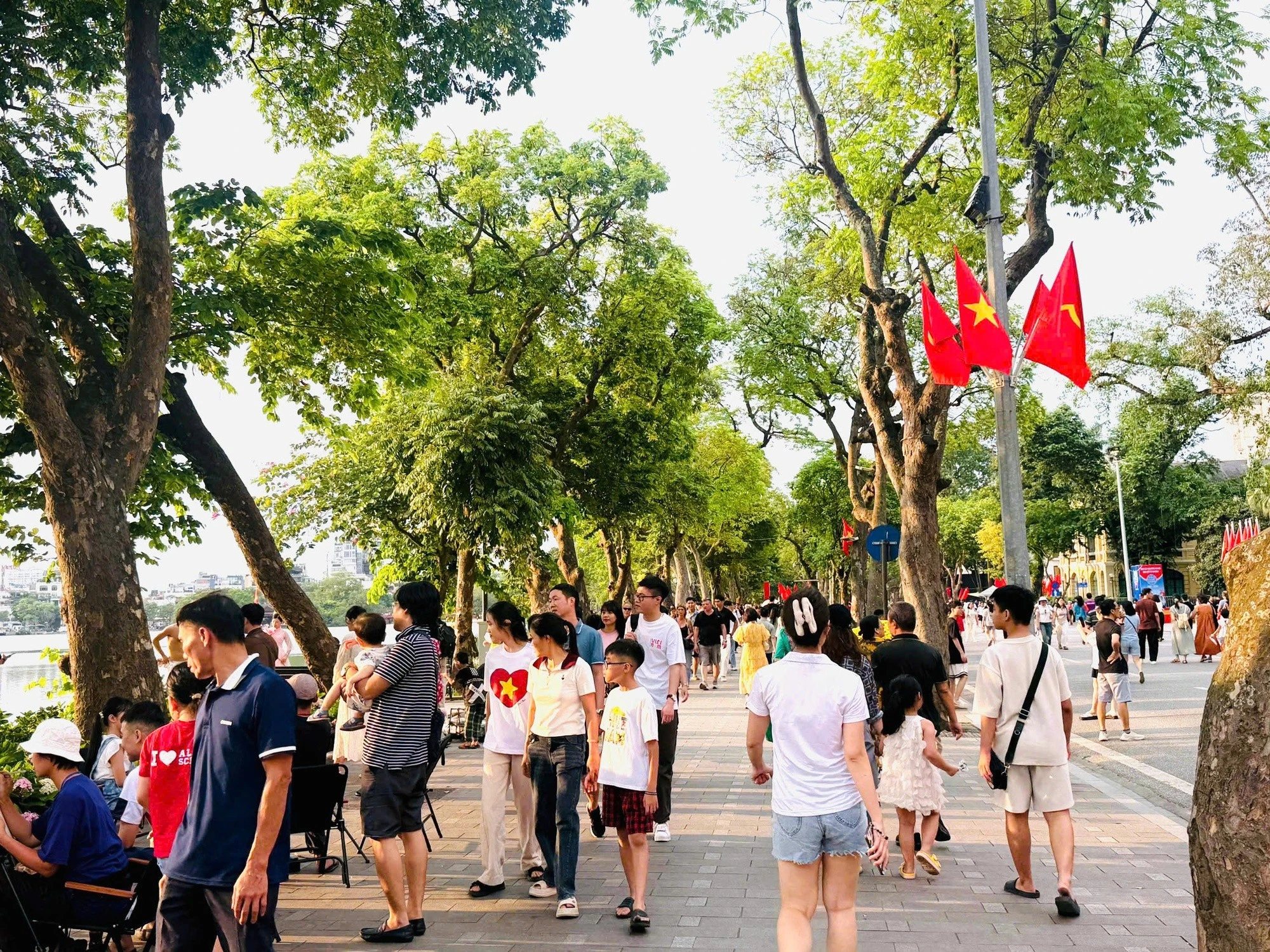 Người dân Thủ đô đi bộ trong không gian xanh mát bên hồ Hoàn Kiếm.