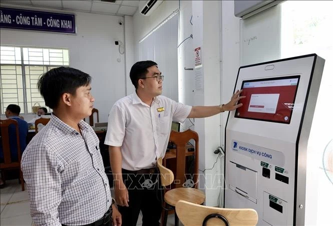Cán bộ Trung tâm Phục vụ hành chính công phường Long Xuyên (An Giang) hướng dẫn người dân thực hiện thủ tục trực tuyến trên Cổng Dịch vụ công quốc gia. Ảnh minh họa: Thanh Sang/TTXVN