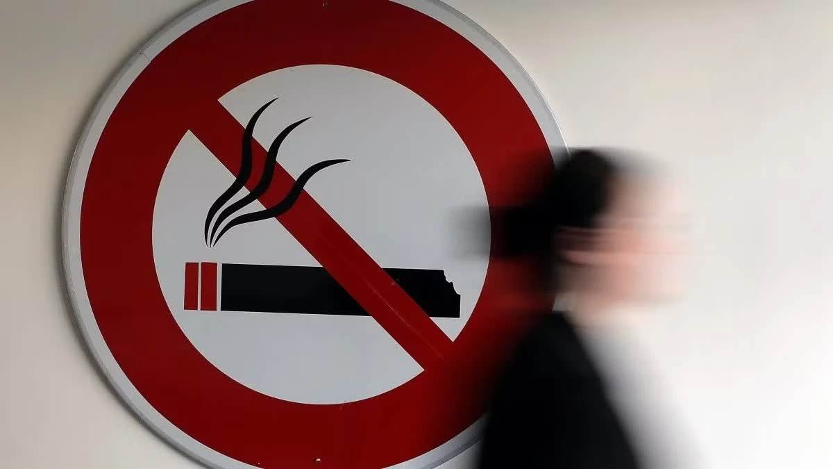 Một phụ nữ đi qua tấm biển cấm hút thuốc nơi công cộng. (Ảnh: Reuters)