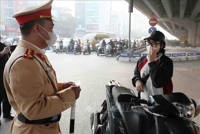 Cảnh sát giao thông xử lý một trường hợp điều khiển xe máy vượt đèn đỏ. Ảnh: Phạm Kiên/TTXVN