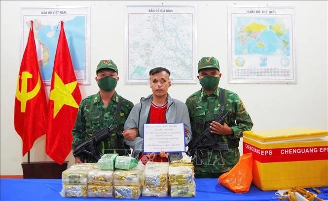 Đối tượng Trình Văn Thông (giữa) cùng tang vật bị lực lượng chức năng thu giữ. Ảnh: TTXVN phát