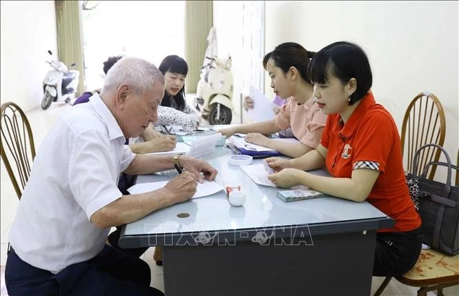 Người cao tuổi ký nhận tiền hỗ trợ từ gói an sinh xã hội. Ảnh: TTXVN
