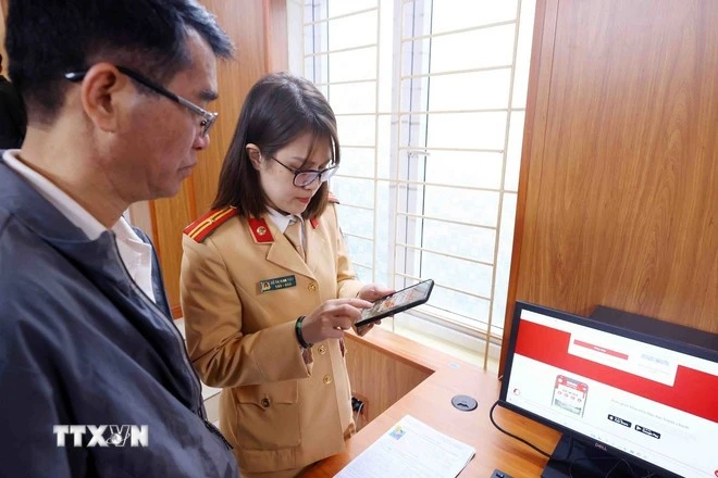 Cán bộ, chiến sỹ Đội Sát hạch, cấp giấy phép lái xe cơ giới đường bộ (Phòng Cảnh sát giao thông, Công an thành phố Hà Nội) hướng dẫn người dân đăng ký làm thủ tục cấp, đổi giấy phép lái xe trên Cổng dịch vụ công quốc gia và ứng dụng VNeID.