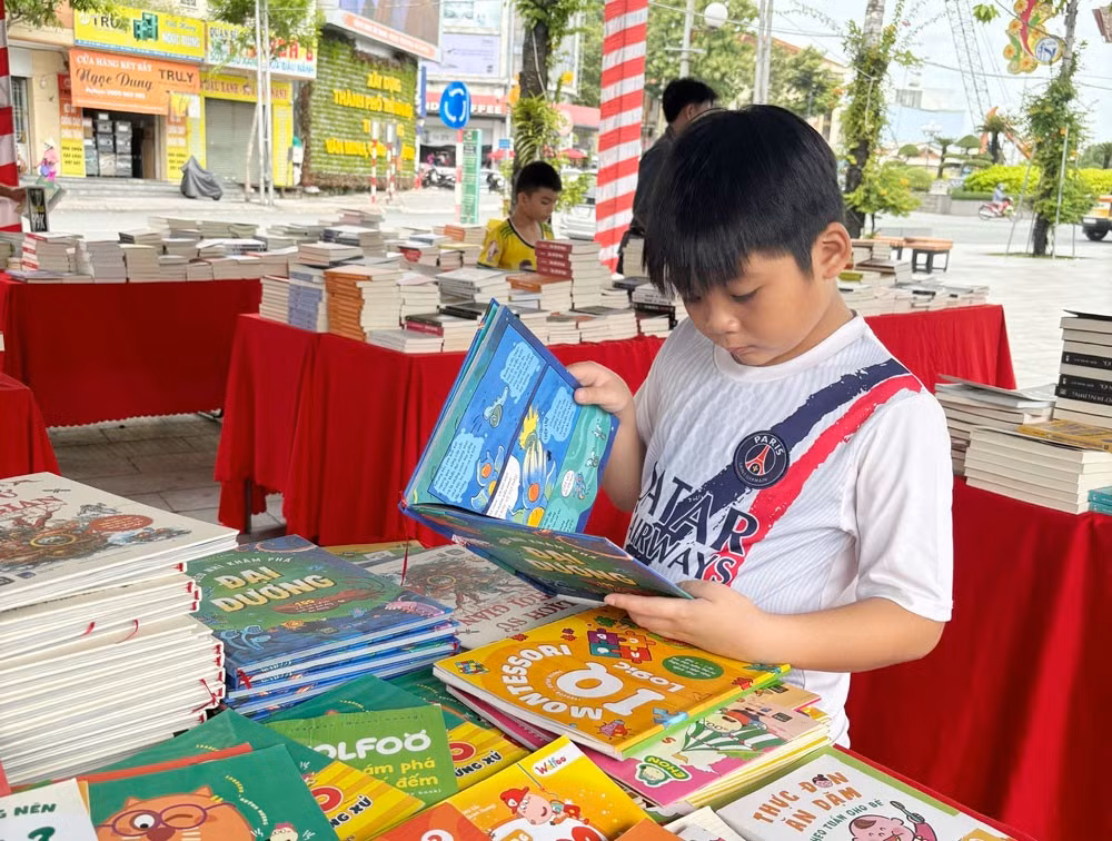 Một bạn thiếu nhi say sưa với quyển truyện tranh tại Hội sách hè được tổ chức ở Công viên ngã 6, phường Phú Cường, TP.Thủ Dầu Một.