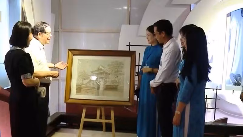 Ông Chu Đức Tính (người thứ 2 bên trái) giới thiệu về bức tranh thêu “Chùa Một Cột”.