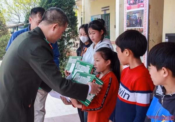 Đại tá Trần Duy Hiển, Phó Tổng Biên tập Báo CAND trao quà cho các em học sinh.