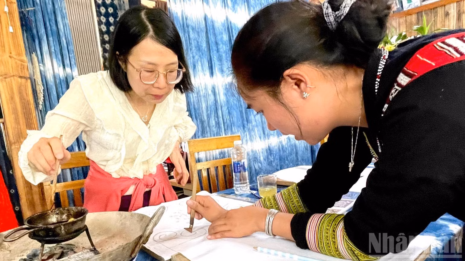Hướng dẫn du khách cách sử dụng bút vẽ sáp ong. (Ảnh: NGỌC LIÊN)