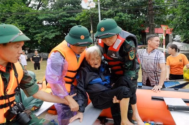 Cụ Nguyễn Thị Kỳ, 98 tuổi, ở xã Sơn Đông, huyện Lập Thạch, tỉnh Vĩnh Phúc được các chiến sĩ bộ đội giúp đỡ đưa lên thuyền cứu hộ đưa đến nơi an toàn.