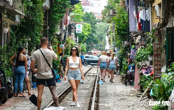 Du khách nước ngoài chụp ảnh tại cà phê đường tàu ở Hà Nội.