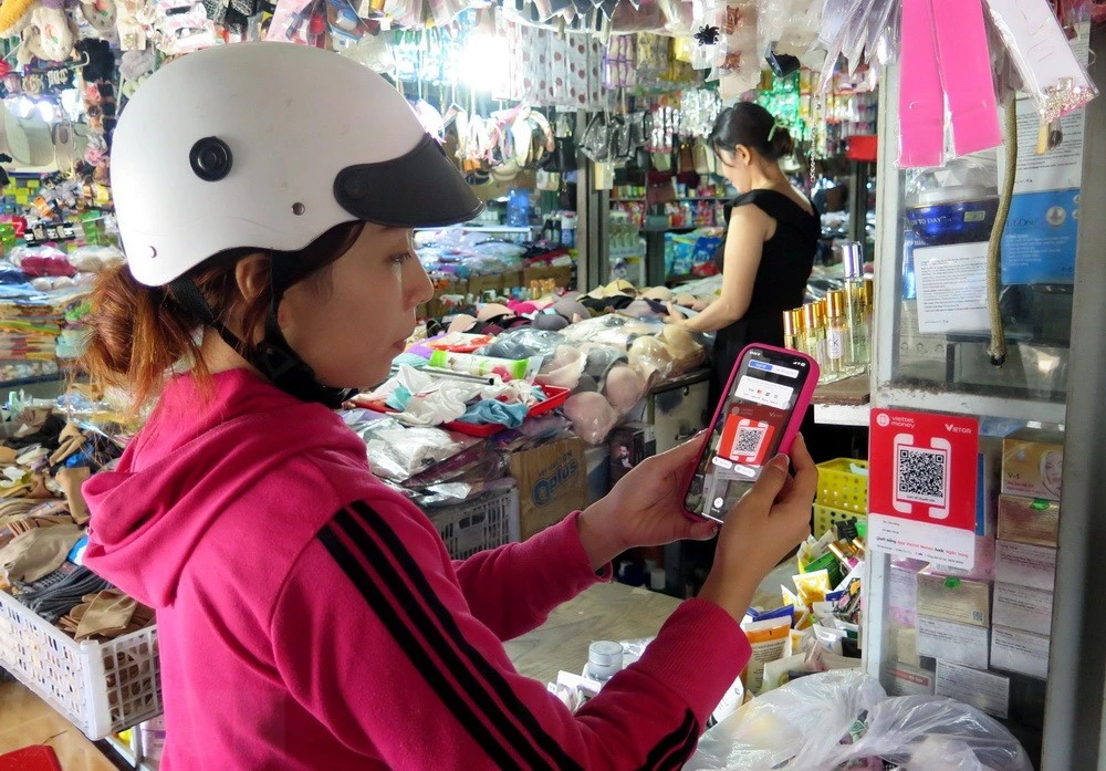 Người dân quét mã QR thanh toán không dùng tiền mặt tại chợ Phù Cát, thị trấn Ngô Mây, tỉnh Bình Định.