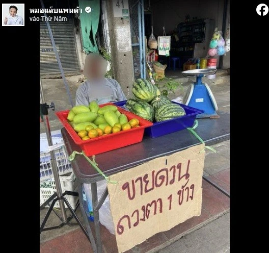 Người đàn ông treo biển rao bán mắt ở quầy trái cây.