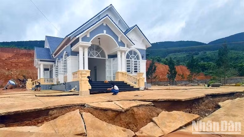 Sân trước ngôi nhà của ông Thắng bị nứt toác, phía sau nhà bị đất sạt trượt.