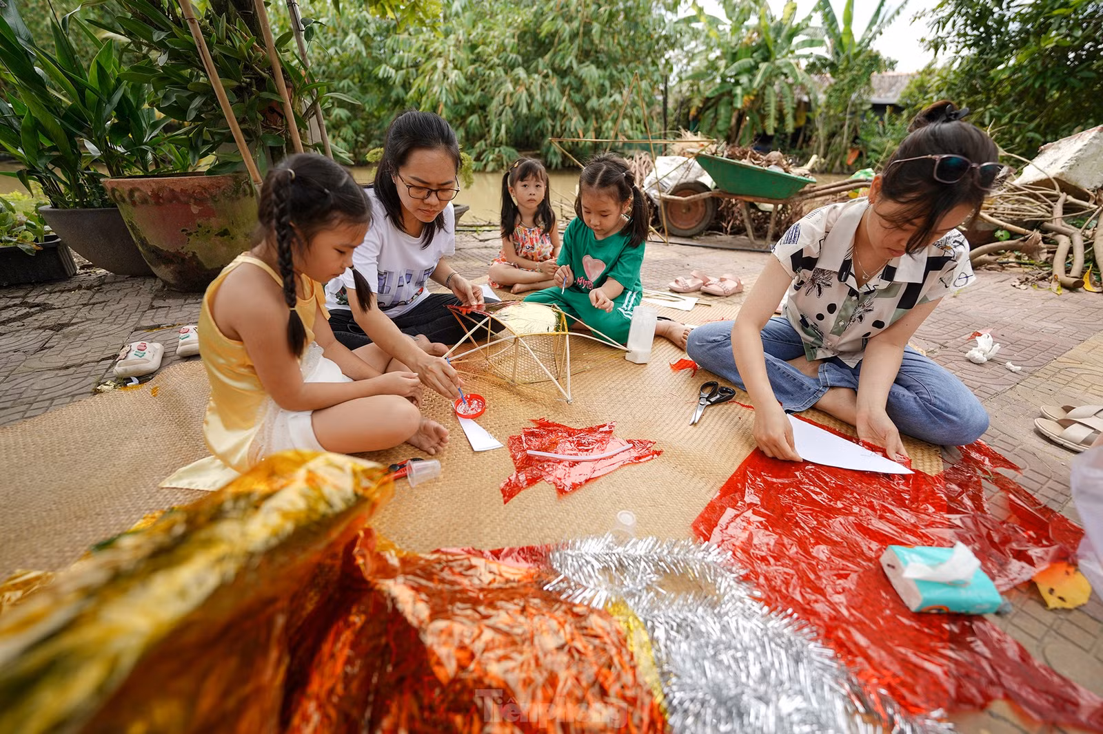 "Vườn nhà chị Lan có nhiều tre. Từ mấy ngày trước, nghe chúng tôi nói có ý muốn làm lồng đèn cho mấy cháu đón trung thu nên anh Tuấn chồng chị Lan đi chẻ tre rồi vót để chị em bày cho mấy đứa nhỏ làm lồng đèn", chị Kim Thoa (áo sơ mi) kể.
