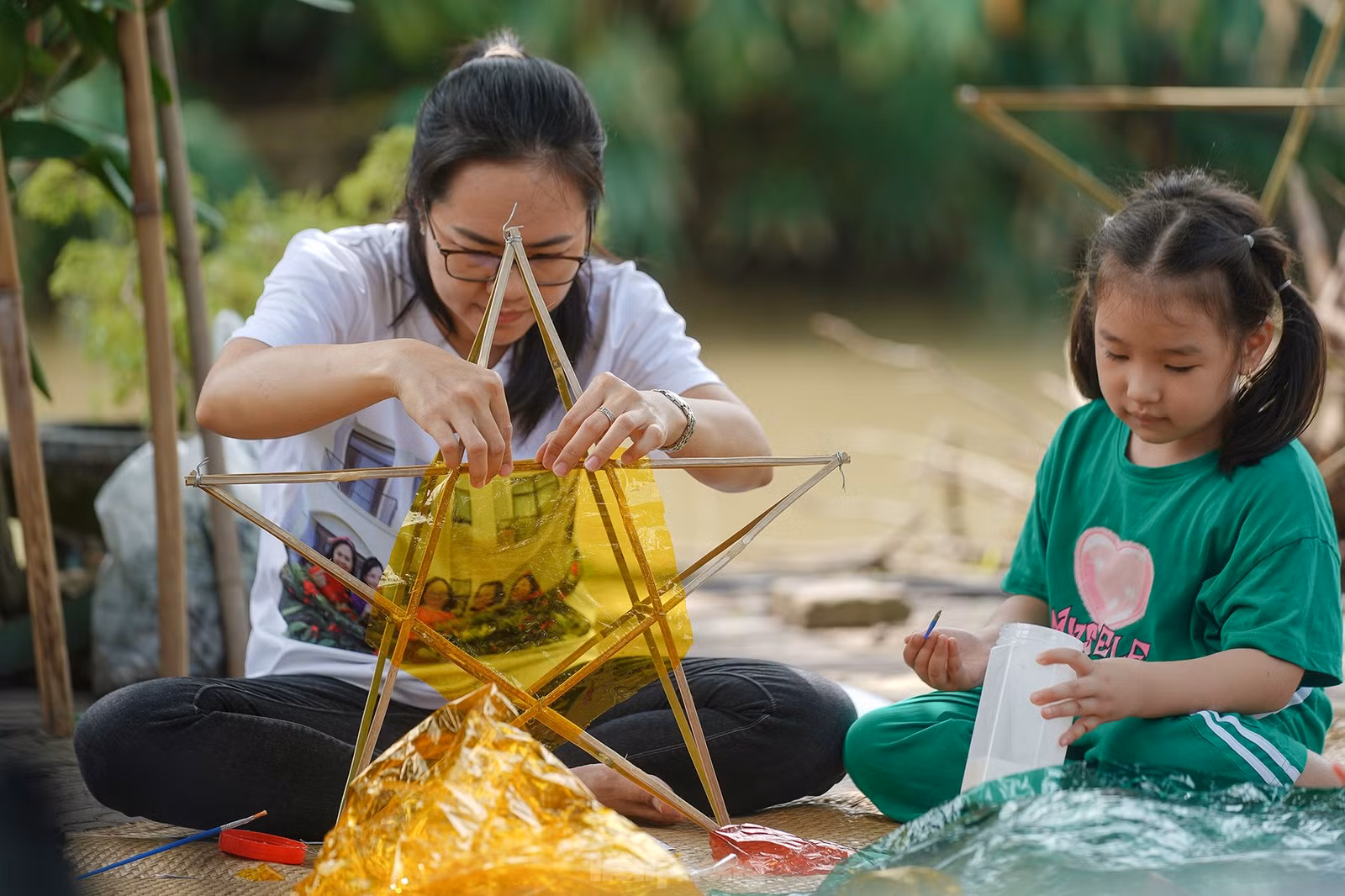 "Công đoạn nào khó thì người lớn sẽ làm phụ các con. Mấy bé thích cầm cọ quét keo và dán giấy kính. Hoạt động này cũng một phần giáo dục các bé về nét văn hóa mà ngày nay ít thấy nữa khi lồng đèn gắn pin, phát nhạc bán đại trà. Chiếc đèn ông sao truyền thống có hình sao vàng năm cánh. Đây cũng là hình ảnh quen thuộc chúng ta vẫn thường thấy trên lá quốc kỳ", chị Hồng Nhung (áo trắng) chia sẻ.