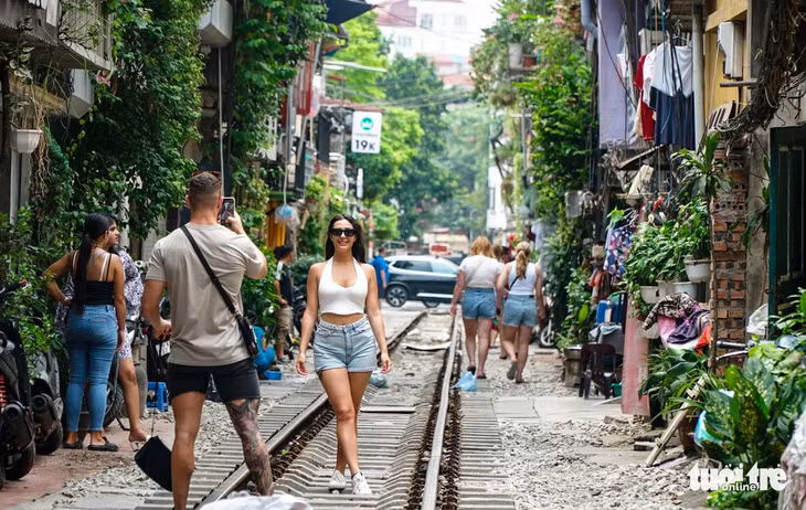 Du khách nước ngoài chụp ảnh tại cà phê đường tàu ở Hà Nội.