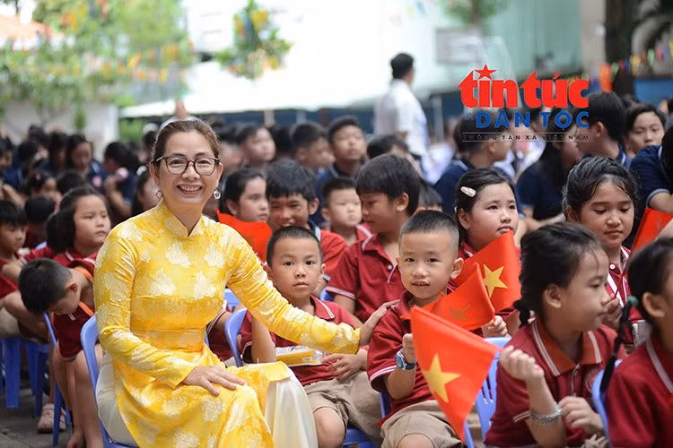 Cô giáo và các em học sinh rạng rỡ trong ngày khai giảng năm học mới, những lá cờ Tổ quốc tạo nên không khí vui tươi, phấn khởi.