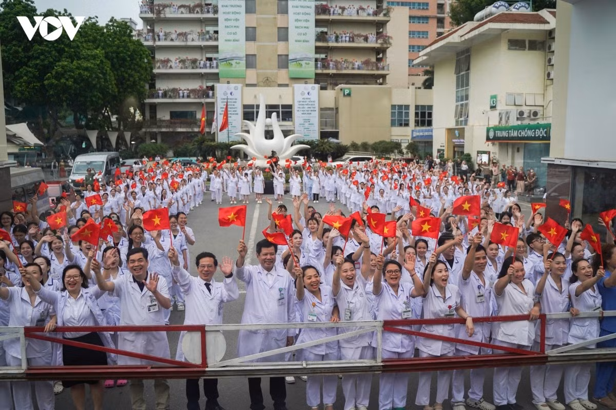 Các y bác sĩ tại cơ sở Hà Nội đứng thẳng hàng, trên tay là lá cờ đỏ sao vàng vẫy chào đoàn đi cơ sở Ninh Bình thực hiện nhiệm vụ khám chữa bệnh.