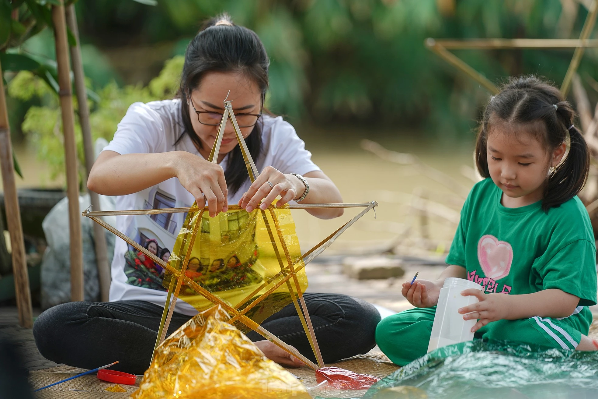 "Công đoạn nào khó thì người lớn sẽ làm phụ các con. Mấy bé thích cầm cọ quét keo và dán giấy kính. Hoạt động này cũng một phần giáo dục các bé về nét văn hóa mà ngày nay ít thấy nữa khi lồng đèn gắn pin, phát nhạc bán đại trà. Chiếc đèn ông sao truyền thống có hình sao vàng năm cánh. Đây cũng là hình ảnh quen thuộc chúng ta vẫn thường thấy trên lá quốc kỳ", chị Hồng Nhung (áo trắng) chia sẻ.