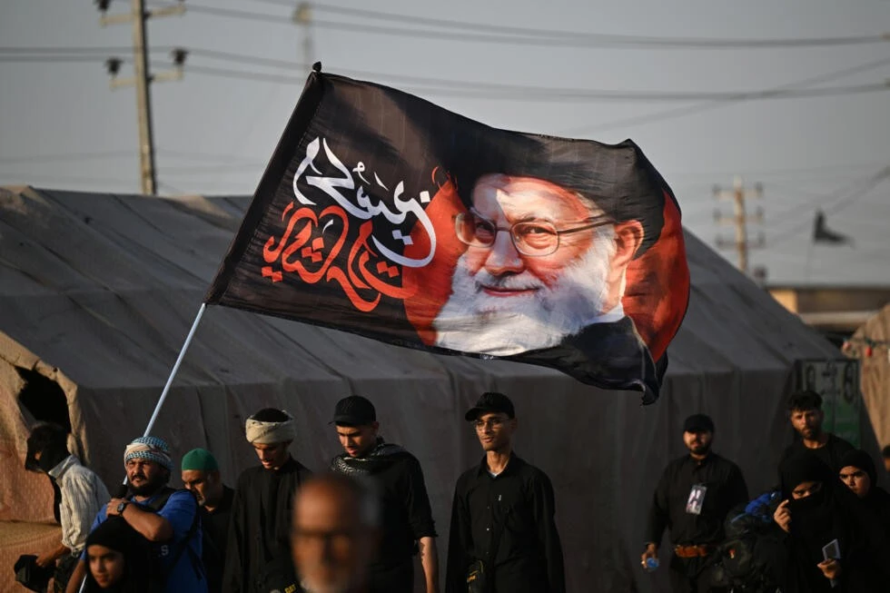 Shiite Muslim pilgrims hold a flag bearing the portrait of Iran's slain supreme leader Ayatollah Ali Khamenei as they march to the Iraqi city of Karbala