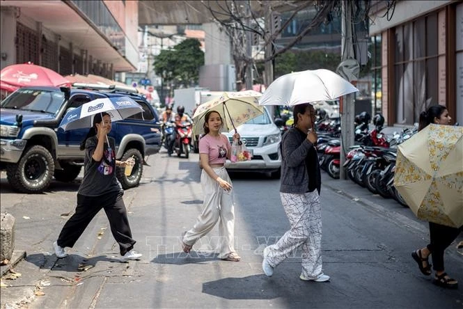 Người dân dùng ô che nắng khi di chuyển trên phố ở Bangkok, Thái Lan.