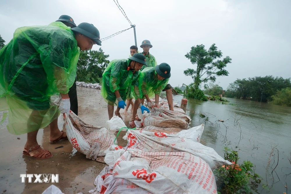 Cán bộ, chiến sỹ Trung đoàn 102 hỗ trợ người dân đắp bao tải đất gia cố đê sông Tích.