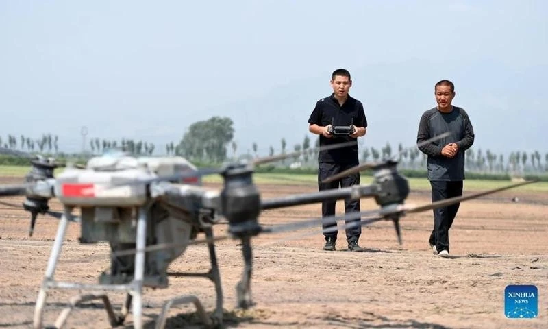 "Nông dân mới" Triệu Vĩnh Tráng (trái) vận hành máy bay không người lái phun thuốc trừ sâu trên một cánh đồng ở xã Bắc Trương, huyện Văn Thủy, tỉnh Sơn Tây, miền Bắc Trung Quốc tháng 8/2024.