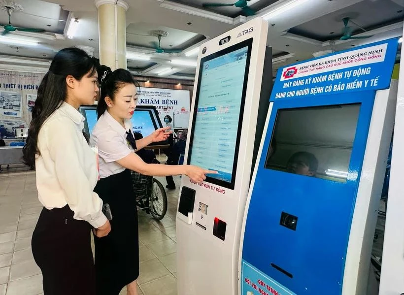 Nhân viên y tế hướng dẫn người dân tại máy đăng ký khám bệnh tự động ở Bệnh viện Đa khoa tỉnh Quảng Ninh.