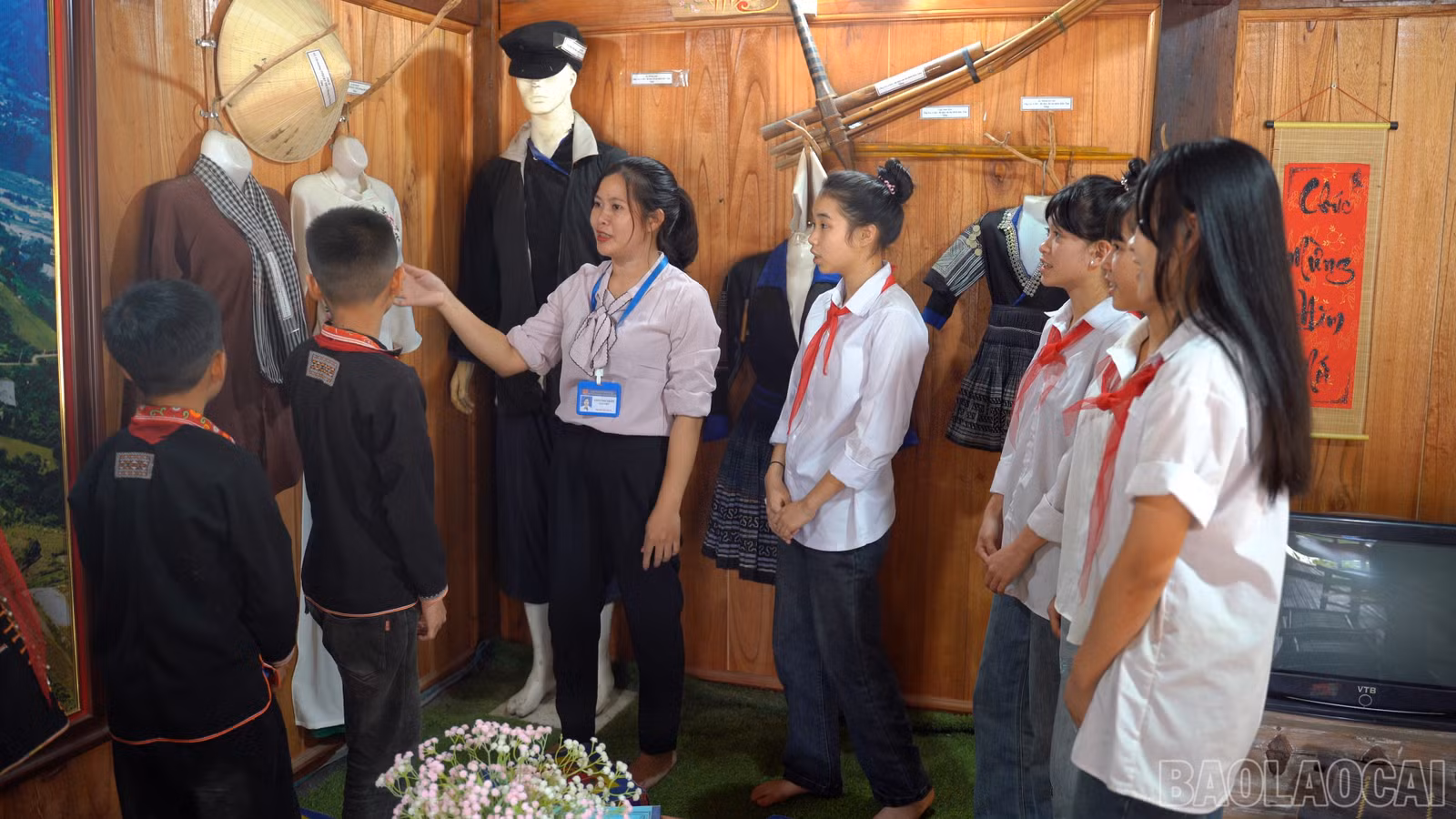 Cô giáo cùng học sinh tham quan nhà truyền thống, lắng nghe những câu chuyện về lịch sử, văn hóa quê hương để thêm hiểu và trân trọng cội nguồn.