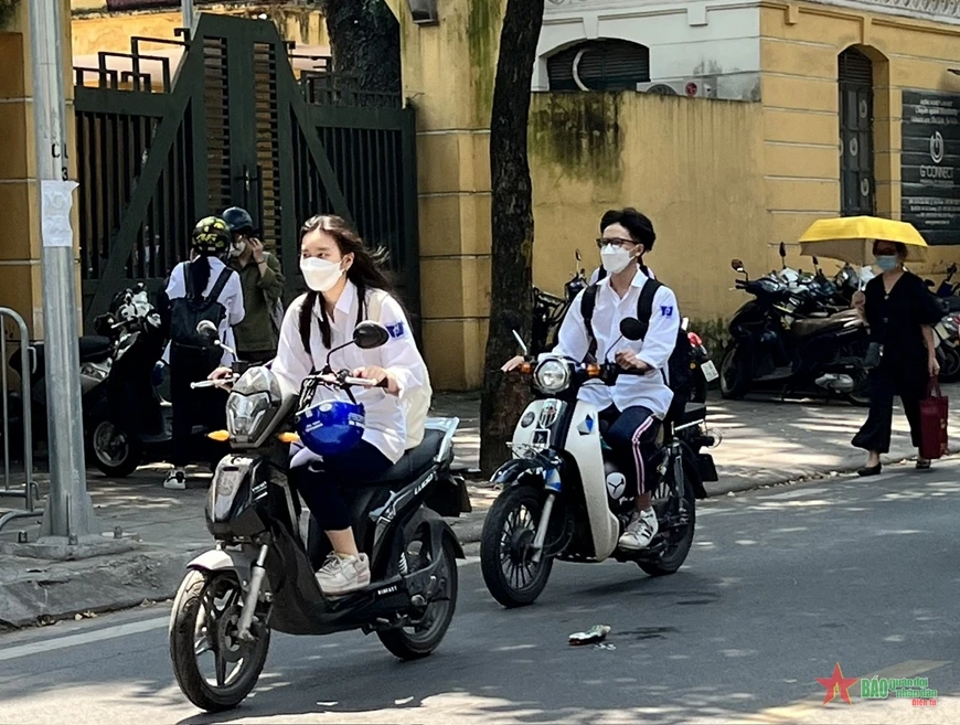 Học sinh điều khiển xe gắn máy, xe điện nhưng không đội mũ bảo hiểm khi tham gia giao thông tại Hà Nội.