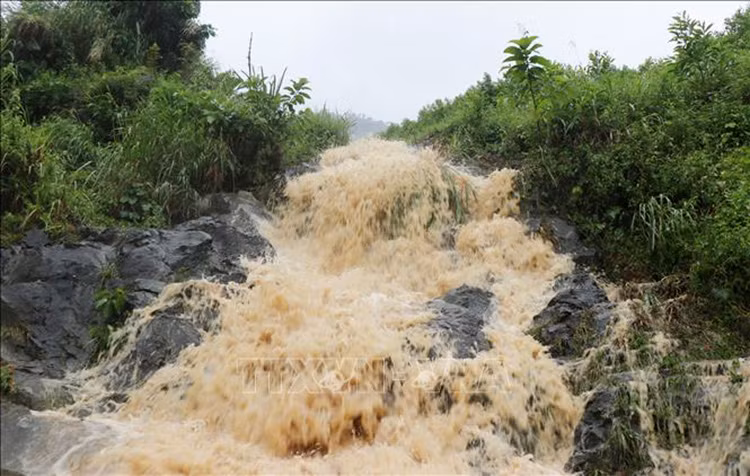Mưa lớn khiến nước từ đỉnh đèo đổ xuống mặt đường Quốc lộ 24 (tỉnh Khánh Hòa). Ảnh: Phạm Cường-TTXVN