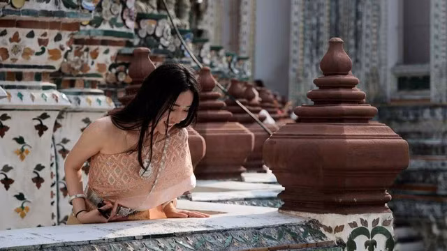 Một du khách mặc trang phục truyền thống của Thái Lan đến thăm chùa Wat Arun ở Bangkok. Ảnh: Reuters