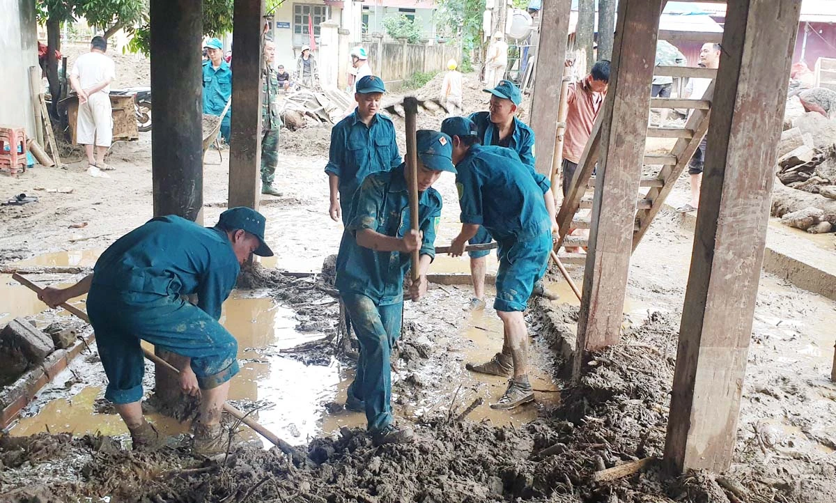 Lực lượng dân quân hỗ trợ nhân dân khắc phục hậu quả lũ ống.